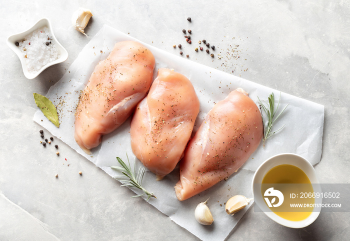 Raw chicken breast with spices on a light background top view