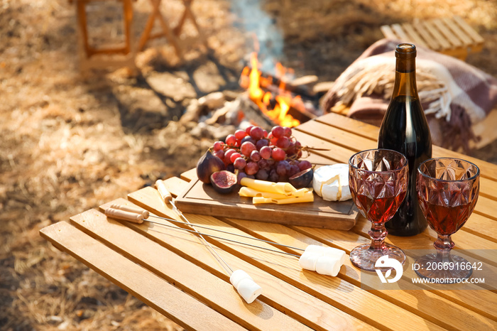 Red wine with tasty snacks on table in autumn forest