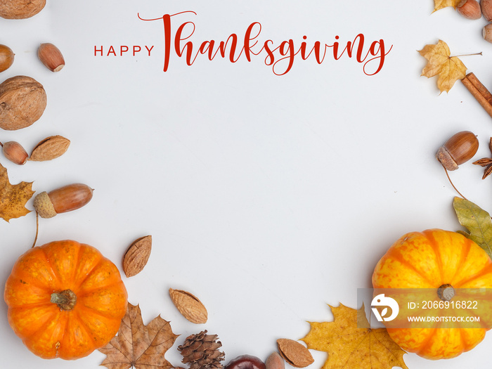 Thanksgiving Greetings. Pumpkins and dry leaves on a white background. Top view.