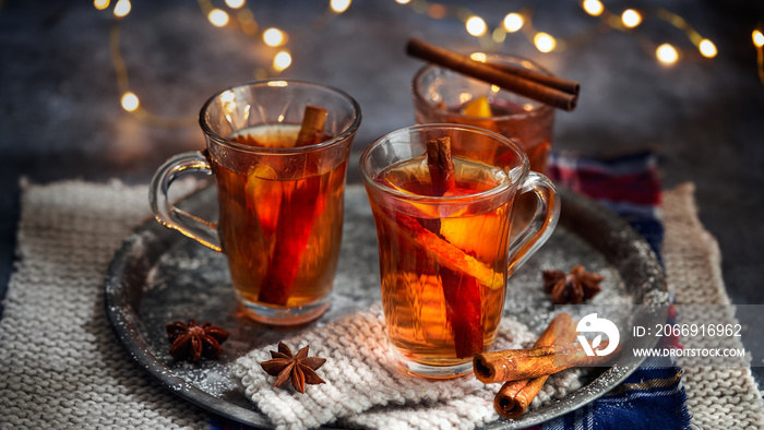 Hot drink for New Year, Christmas or autumn holidays. Mulled cider or spiced punch, tea or mulled white wine with lemon, apples, cinnamon, anise, cloves on a dark background. No People.