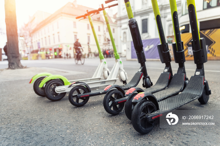 Many modern electric kick scooters sharing parked on city street. Self-service stree transport rental service. Rent urban mobility vehicle with smartphone application. Zero emission green eco energy.