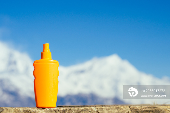 sunscreen in an orange bottle on a mountain background. the concept of preventing skin cancer and the use of sunscreen in the mountains.