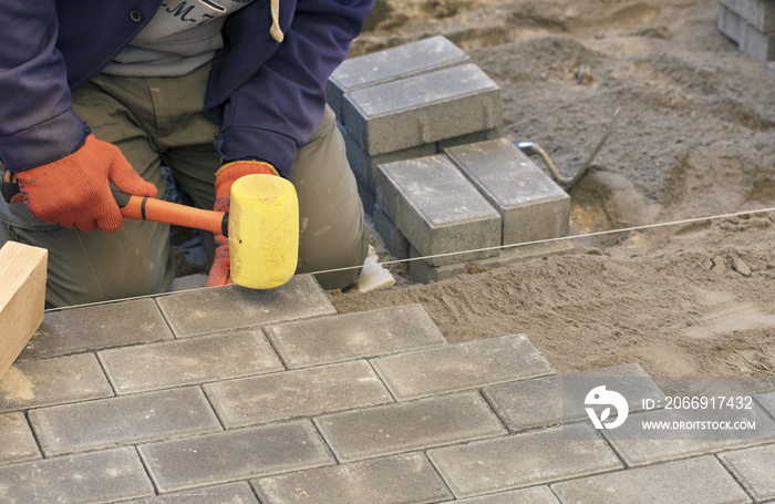 Paving the tiles on the sidewalk, the worker lay the tile, aligning it on the thread