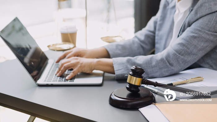 Justice and law concept.Male judge in a courtroom with the gavel, working with, computer and docking keyboard, eyeglasses, on table in morning light