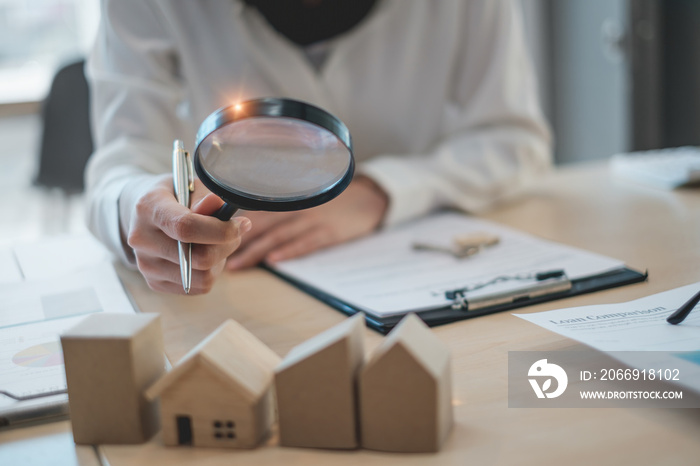 A woman holding magnifying glass and checking house model .Real Estate House Appraisal And Inspection concept.