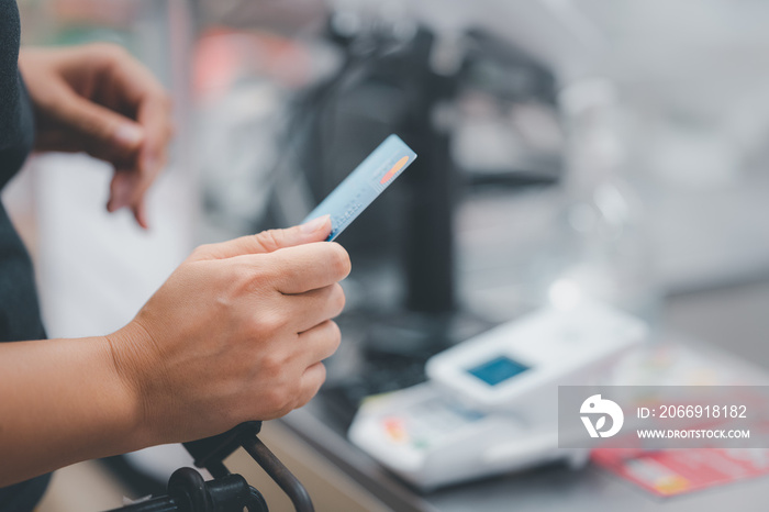 Woman at the supermarket checkout, she is paying using a credit card, shopping and retail concept