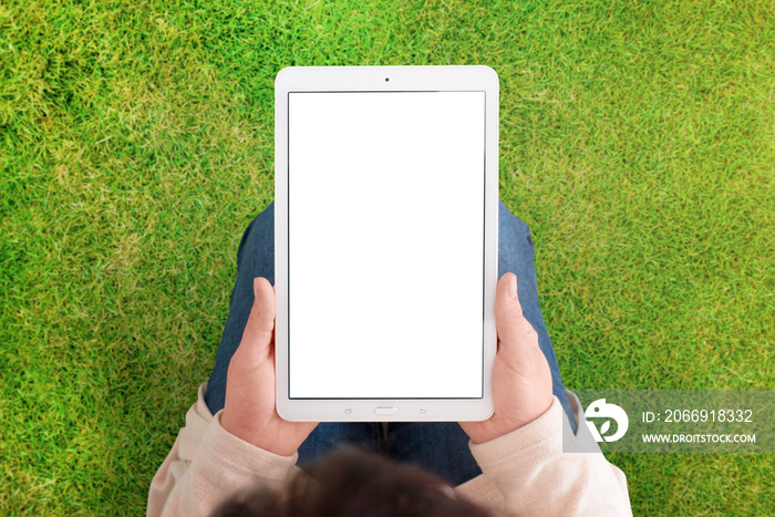 Tablet mockup with green grass, meadow in background. Woman hold white tablet with isolated screen in vertical position. White, blank screen for app or web site promotion.