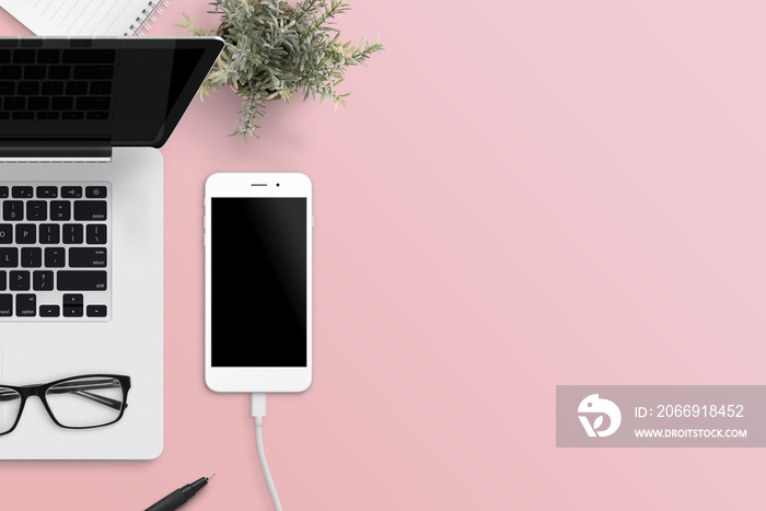 Flat lay scene of smart phone and laptop on office desk. Pink surface. Flat lay.