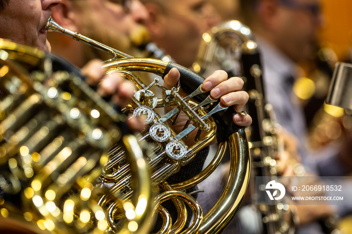 Young woman playing on french horn during philharmonic concert