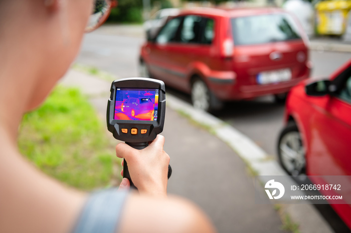 Young woman measuring heat in the street with the thermometer. Global warming analysis.