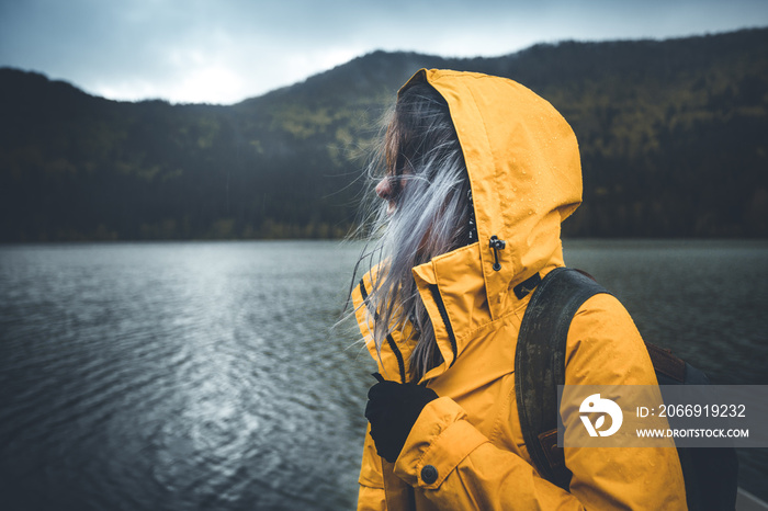 Active outdoors people lifestyle. Close up view of a hiker enjoying rainy weather. Outdoors adventure trek activity, hiker wearing yellow waterproof raincoat sportswear clothes