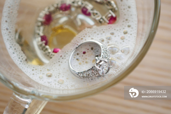 cleaning vintage jewelry diamond ring and bracelet in glass on wood table background