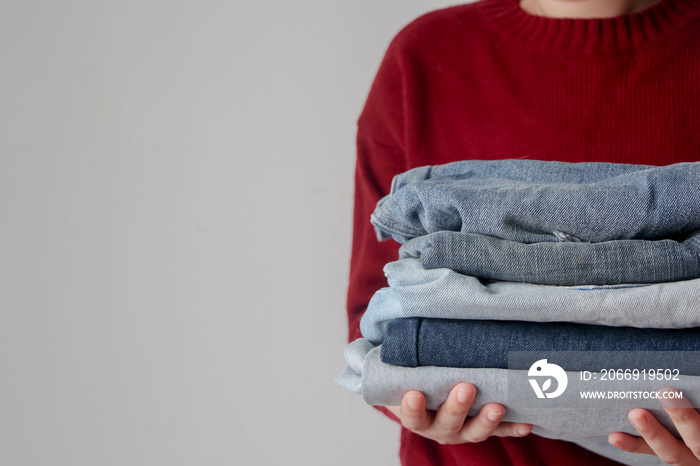 woman holding pile of jeans on white background