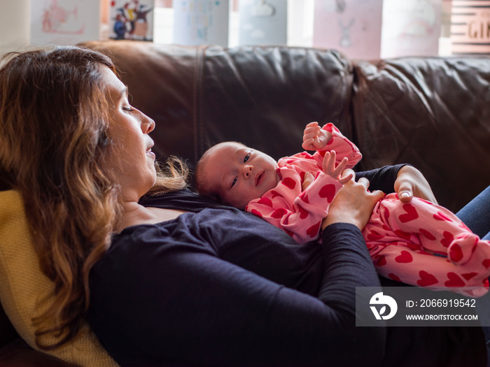 Mother lying on sofa with infant daughter