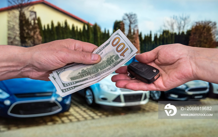 Male hand gives money and take car keys, new car as background