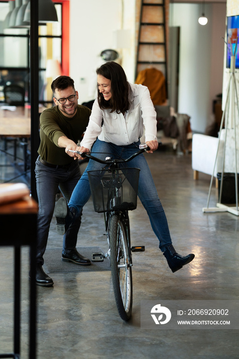 Colleagues in office. Businesswoman and businessman with bicycle. Two friends having fun together