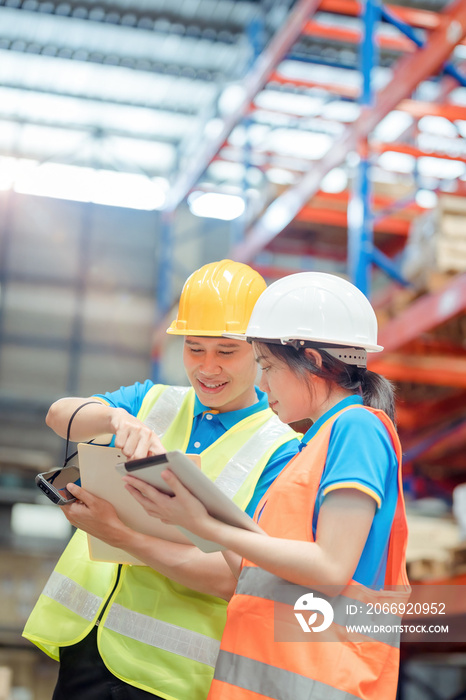 Asian engineer in helmets order and checking goods and supplies on shelves with goods background in warehouse.logistic and business export ,Warehouse worker checking packages on shelf in a large store