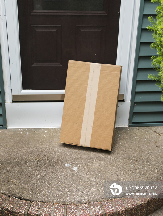 A brown package is left vulnerable at front door