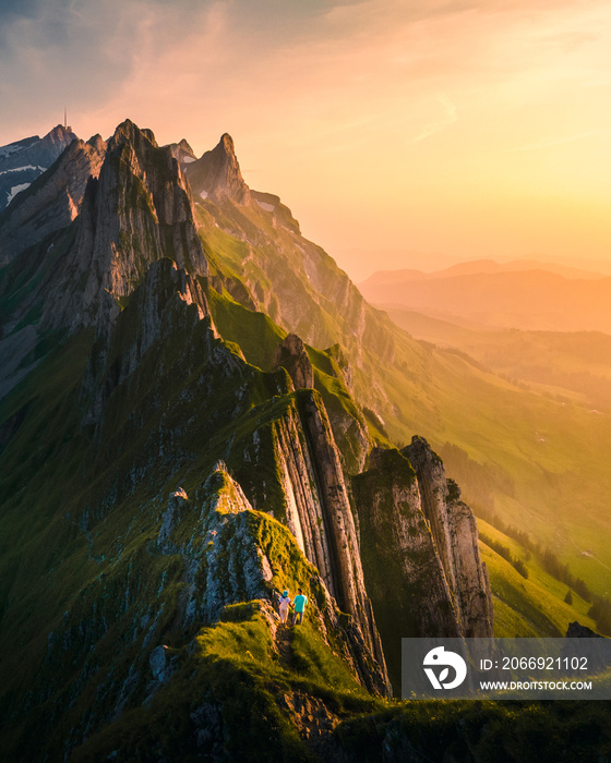 couple men and woman on vacation in the Swiss Alps Aescher cliff viewed from mountain Ebenalp in the Appenzell region in Switzerland