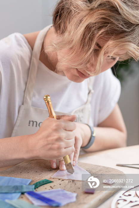 Artist cutting sheets of stained glass into small mosaic squares. Close-up