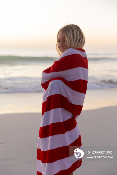 Caucasian woman covering herself with a US flag at the beach