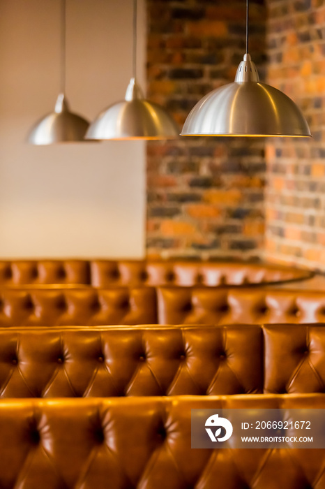 Brown leather restaurant booths with hanging stainless steel ceiling lamps