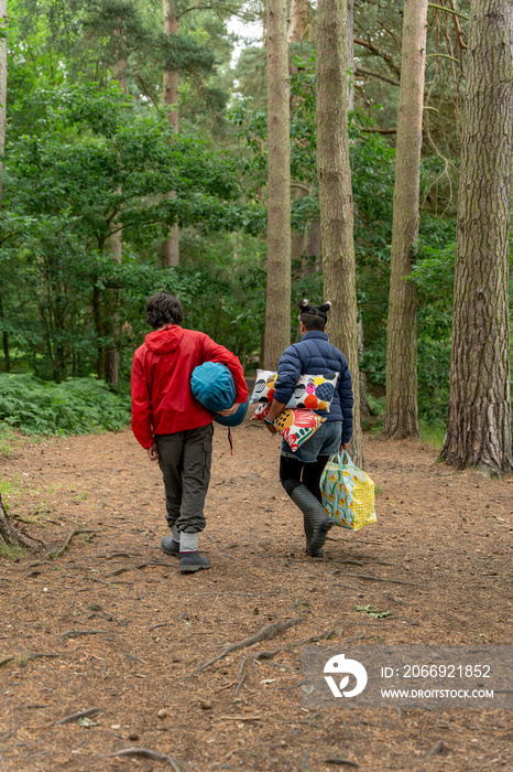 Mother and son walking in forest with camping equipment