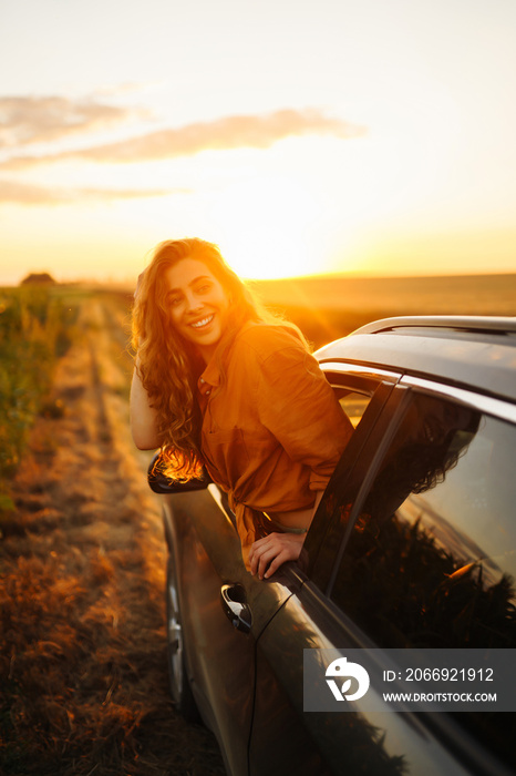 Young woman is resting and enjoying sunset in the car. Lifestyle, travel, tourism, nature, active life.