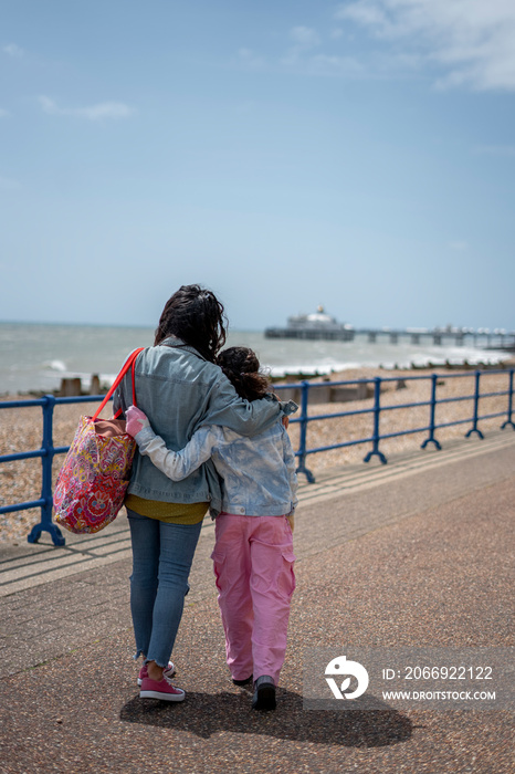 Mother and daughter (8-9) hugging on promenade