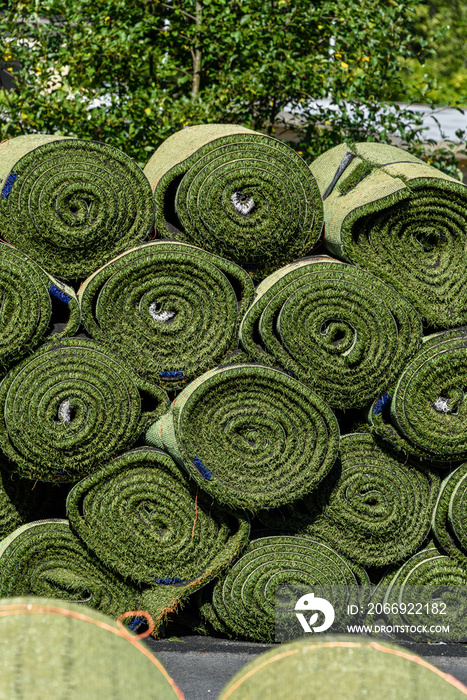 Green rolls of new artificial turf ready for installation on an outdoor sports field