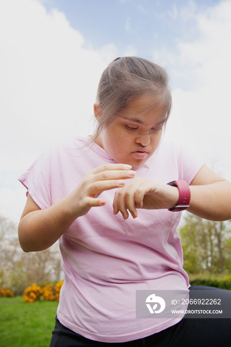 Young curvy girl with Down Syndrome wearing workout clothes and fitness watch