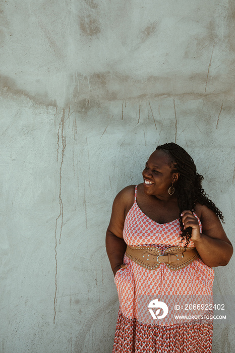 plus size African American woman standing against a wall smiling