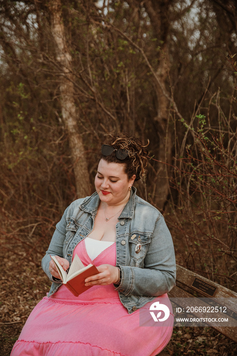 plus size woman reads book on bench