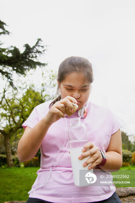 Young curvy girl with Down Syndrome holding reusable water bottle after workout