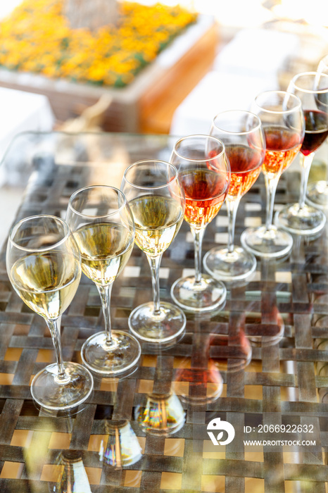 Wine tasting set in the light summer environment. Custom wine tasting concept. Glasses of wine on the glass table and outdoor background