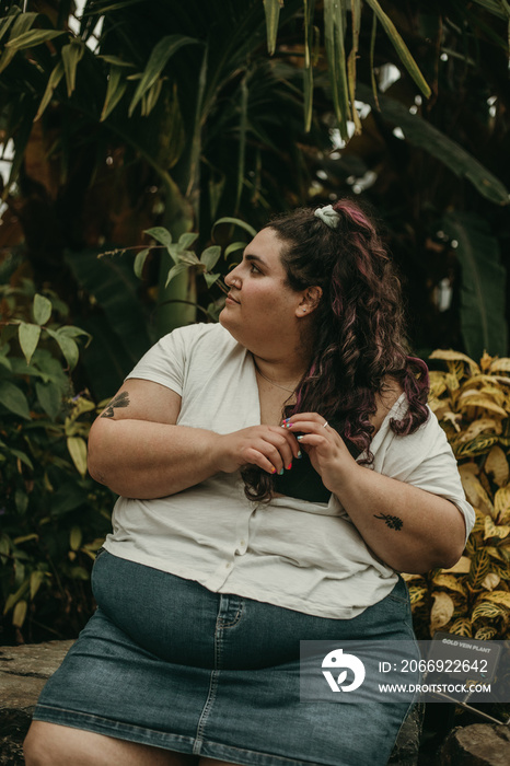 portrait of a plus size woman looking away playing with her hair