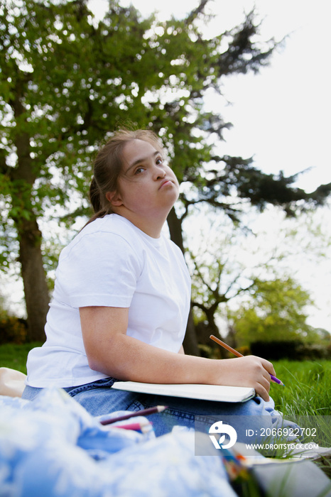 Young mid-sized woman with Down Syndrome writing in journal