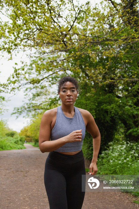 Young curvy woman with vitiligo working out in the park wearing earbuds