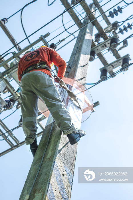 Electrician lineman with safety belt climb electric post power pole to install and repair power lines.