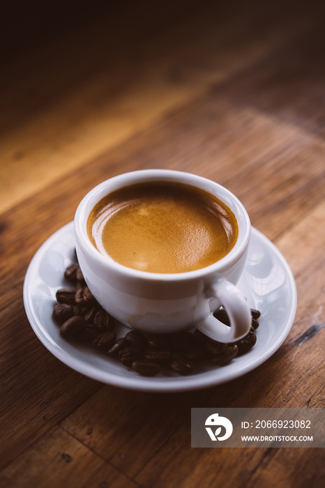 Fresh tasty espresso cup of hot coffee with coffee beans on wood table background