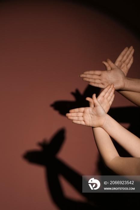 Mother and child performing a shadow play on color background