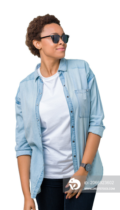 Beautiful young african american woman wearing sunglasses over isolated background looking away to side with smile on face, natural expression. Laughing confident.