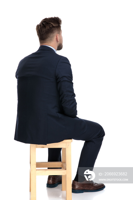 back view of young businessman sitting on wooden chair