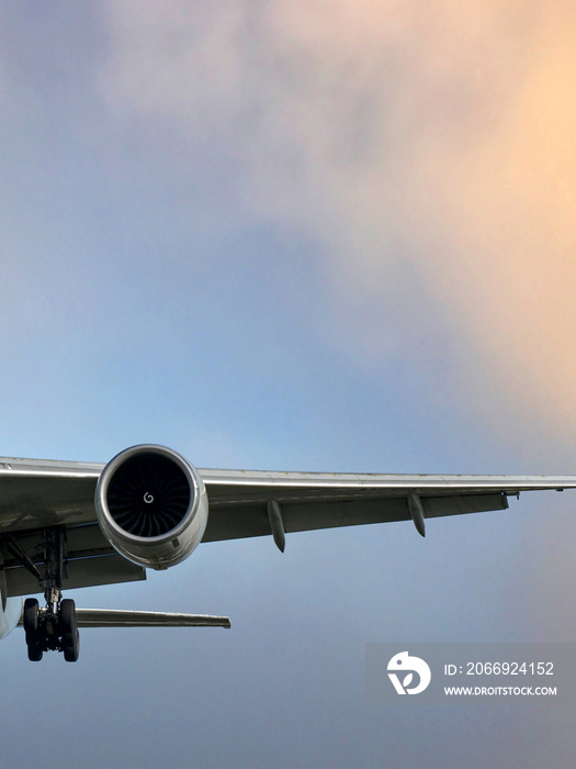 Engine and wing of a modern passenger plane against a colourful cloudy sky.. No people. Copy space.