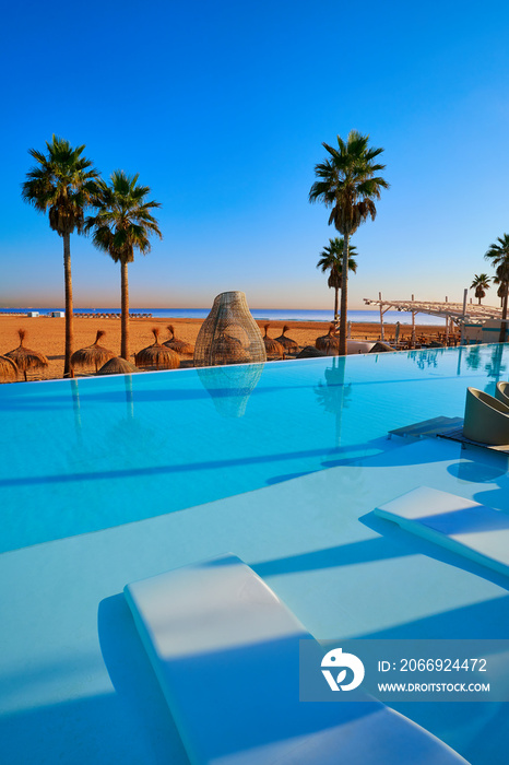 Resort infinity pool in a beach with palm trees