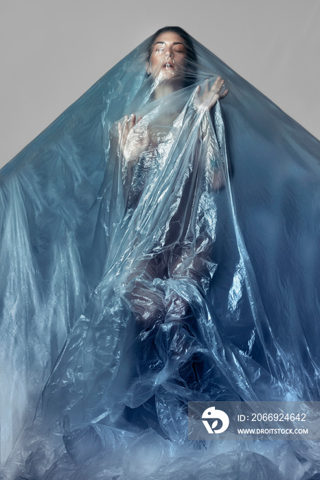 woman under plastic trying to get out, pollution of the seas and rivers. concept portrait