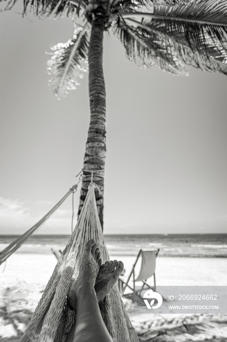 Woman’s legs in the hammock against the ocean view