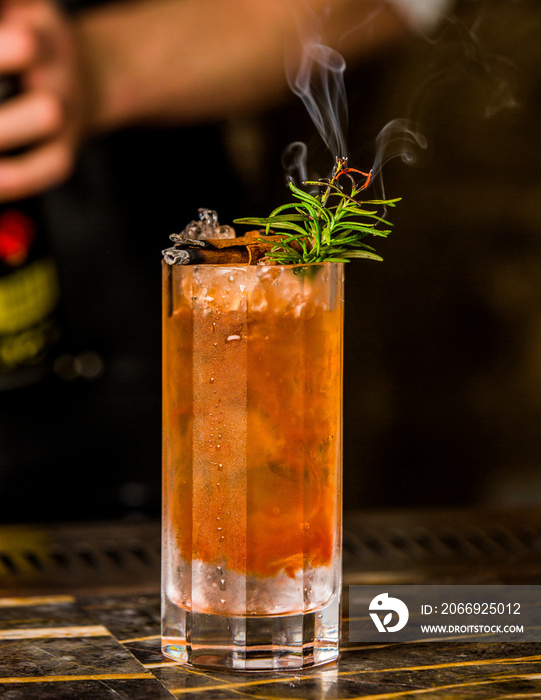 cinnamon pear cocktail garnished with cinnamon stick, ice and rosemary