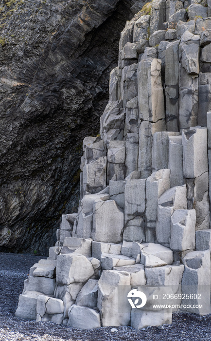 Basalt rock pillars columns at Reynisfjara beach near Vik, South Iceland. Unique geological volcanic formations. Natural stone texture background.