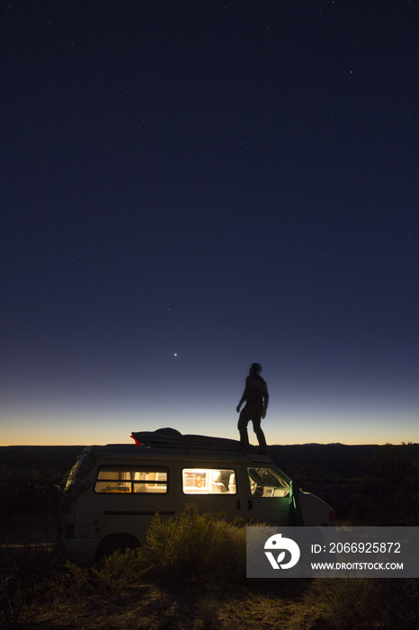 Self portrait of the photographer, Woods Wheatcroft, on top of his van at night while camping near the Virgin Mountains of Nevada.